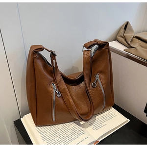 Detail of a brown textured faux leather hobo bag with dual silver zippers and a wide strap