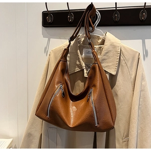 Close-up of brown pebbled leather hobo bag with adjustable strap and dual silver zippers