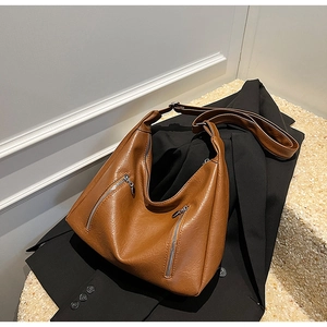 Detail of caramel brown faux leather tote with pebble texture and silver zippers