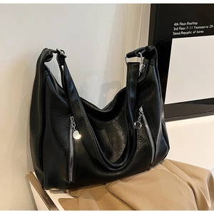 Macro detail of black vintage leather tote bag featuring functional silver zippers