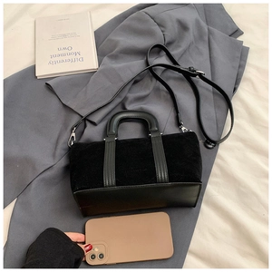 Detailed view of black matte suede and leather handbag with silver hardware and shoulder strap