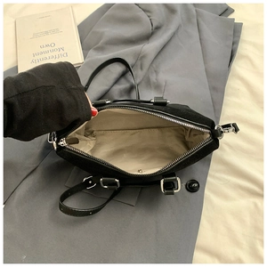 Interior detail of black matte handbag showing tan fabric lining and zip pocket