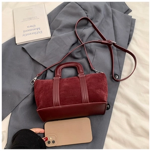 Close-up of wine red suede Boston bag with leather handles on a grey suit jacket