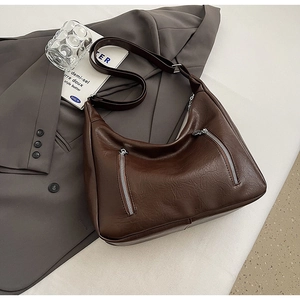 Detail of vintage brown PU leather crossbody bag with silver parallel zippers and wide strap