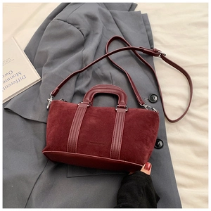 Close-up of burgundy frosted Boston bag with silver hardware on a grey blazer