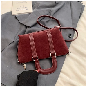 Detailed macro view of burgundy matte suede texture and leather handles on handbag