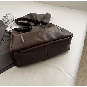Close-up of deep brown pebbled leather tote bag with stylish silver zipper details