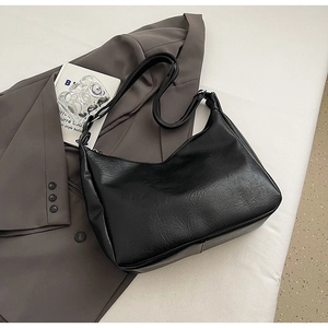 Detailed view of black pebbled leather texture on an elegant minimalist shoulder bag