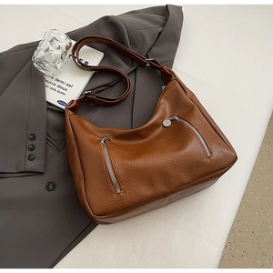 Detail of caramel brown PU leather hobo bag with dual vertical zippers and lycra texture