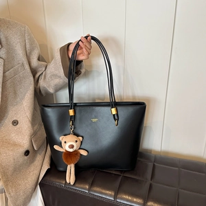 Classic black tote bag for women with a brown knit bear charm and gold logo lettering