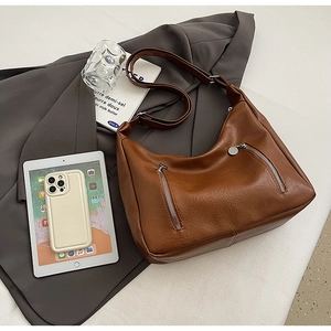 Detail view of brown vintage hobo bag with silver zippers styled on a blazer