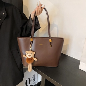 Brown vintage faux leather tote bag with gold lettering and a plush bear pendant