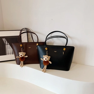 Chic leather tote bags in black and brown featuring bear pendants and gold hardware