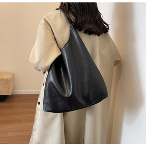 Detail of large black PU leather tote bag worn with a beige coat for a stylish office look