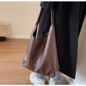 Side view of a dark brown large capacity PU leather tote bag worn by a model