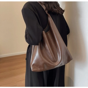 Detail view of coffee brown PU leather tote bag with smooth texture and soft pleats