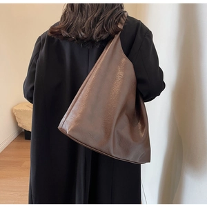 Minimalist deep brown oversized tote bag in textured faux leather styled with a black coat