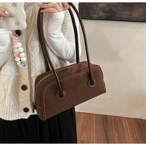Close-up of deep brown suede Boston bag featuring contrast stitching and long leather handles
