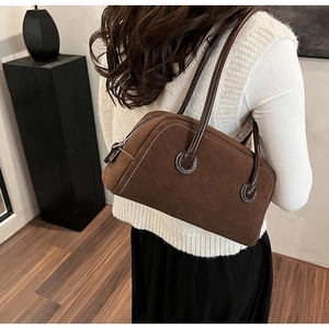 Detail of vintage brown suede Boston bag with white stitching and leather handles
