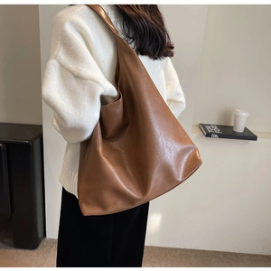Minimalist caramel brown PU leather tote bag shown on shoulder with natural textures