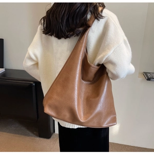 Detail of a large brown PU leather tote bag with vintage texture and minimalist design