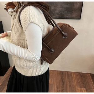 Detail of dark brown suede Boston bag with white contrast stitching on model