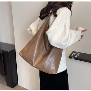 Detail of soft brown PU leather tote bag showing large capacity and smooth texture on model