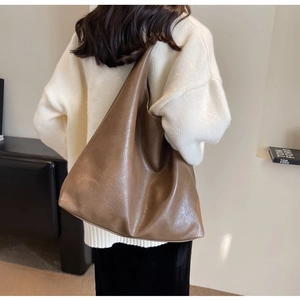 Brown PU leather tote bag shown on a model to display its large capacity and soft texture