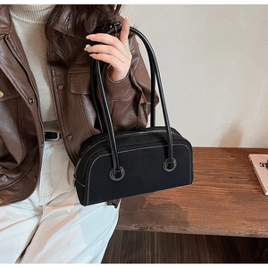 Detail of black canvas baguette bag with white contrast stitching and metal zipper