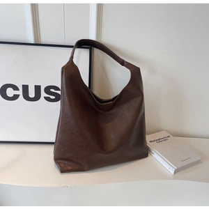 Detail of a large dark brown hobo bag with vintage leather texture and wide strap