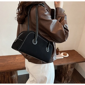 Detail of black suede Boston bag featuring contrast white stitching and slender leather handles
