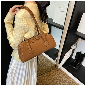 Detail view of brown leather Boston bag with white contrast stitching and dual zippers