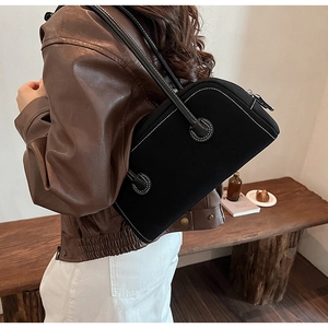 Detail of black suede Boston bag with white contrast stitching and long shoulder handles