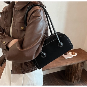 Side view of black suede Boston bag with white stitching shown on shoulder