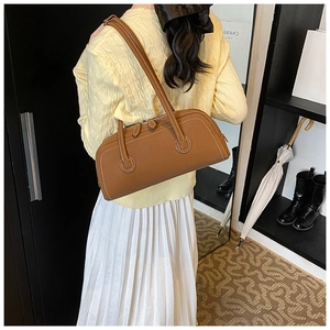 Detail of brown leather tote bag with white contrast stitching and dual zipper closure