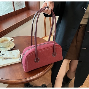 Close-up of retro burgundy suede Boston bag with white contrast stitching and long handles