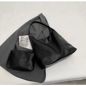 Detail view of black PU leather hobo bag and matching pouch with natural leather texture