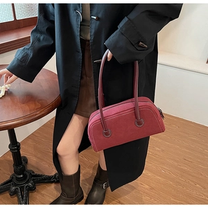 Detail of burgundy faux suede Boston bag with white stitching shown with a model
