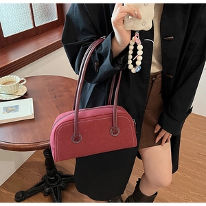 Detail of burgundy suede Boston bag featuring white contrast stitching and long slim handles