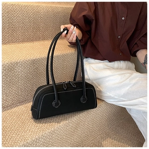 Detail of minimalist black tote bag with white contrast stitching and long dual straps