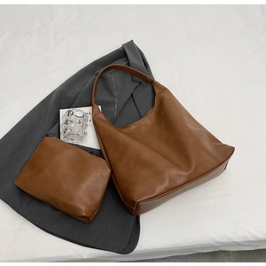 Detailed macro view of a brown PU leather two-piece tote bag set with matching small pouch