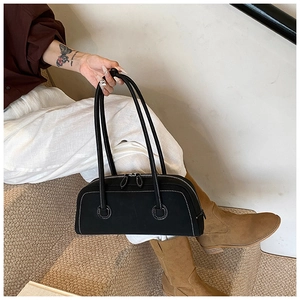 Detail of a black tote bag with white contrast stitching and long handles in a lifestyle setting