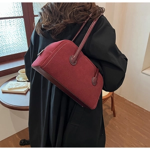 Detail of burgundy suede Boston bag with white stitching and leather trim details