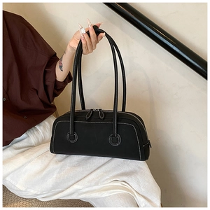 Detail of a vintage black leather tote bag with contrast white stitching and dual zippers