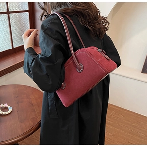 Detail of dark red suede Boston bag with contrast white stitching and shoulder strap