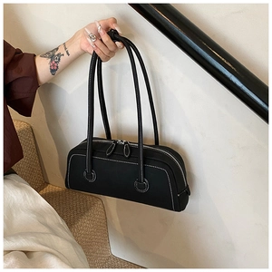 Close-up of black leather tote bag featuring striking white contrast stitching details