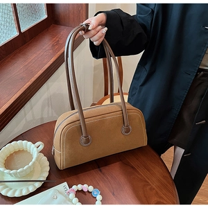 Detailed view of brown suede texture and leather strap on a Boston shoulder bag