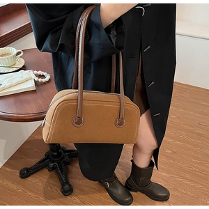 Close-up of brown suede Boston bag with contrast white stitching and leather strap