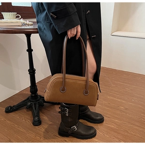 Detail of vintage brown suede boston handbag with leather straps and decorative buckles