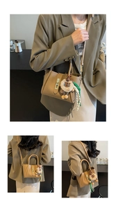 Detail of khaki lychee grain leather bucket bag with metal twist lock and plush bear charm